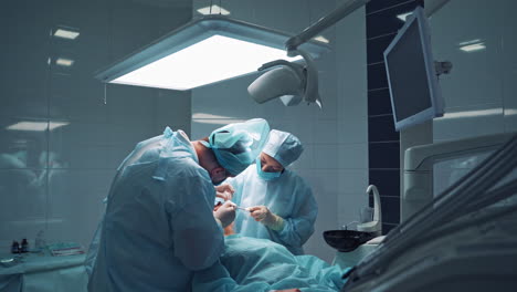 doctors in medical masks are doing tooth treatment in modern stomatology clinic. male professional dentist with his assistant at work. operation procedure.