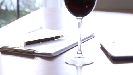 red wine, documents and smartphone on table