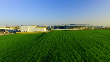 rising above factory in front of a green field