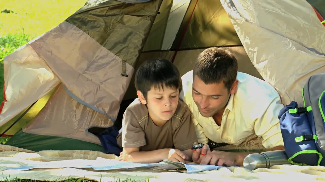 아빠와 아들이 텐트 앞에서 지도를 보고 있다