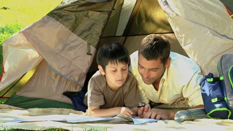 dad and son looking at a map in front of a tent