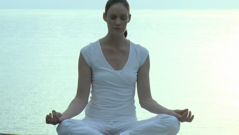 mujer haciendo yoga con el mar en el fondo