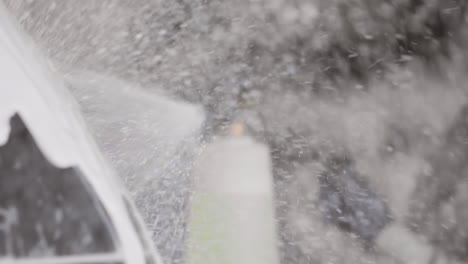 la aplicación de jabón de espuma de pulverización directamente a una superficie brillante del coche