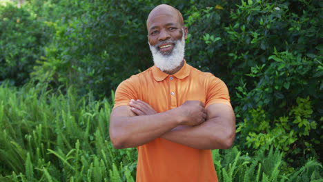 Portrait-of-african-american-senior-man-smiling-and-crossing-his-arms-in-the-garden