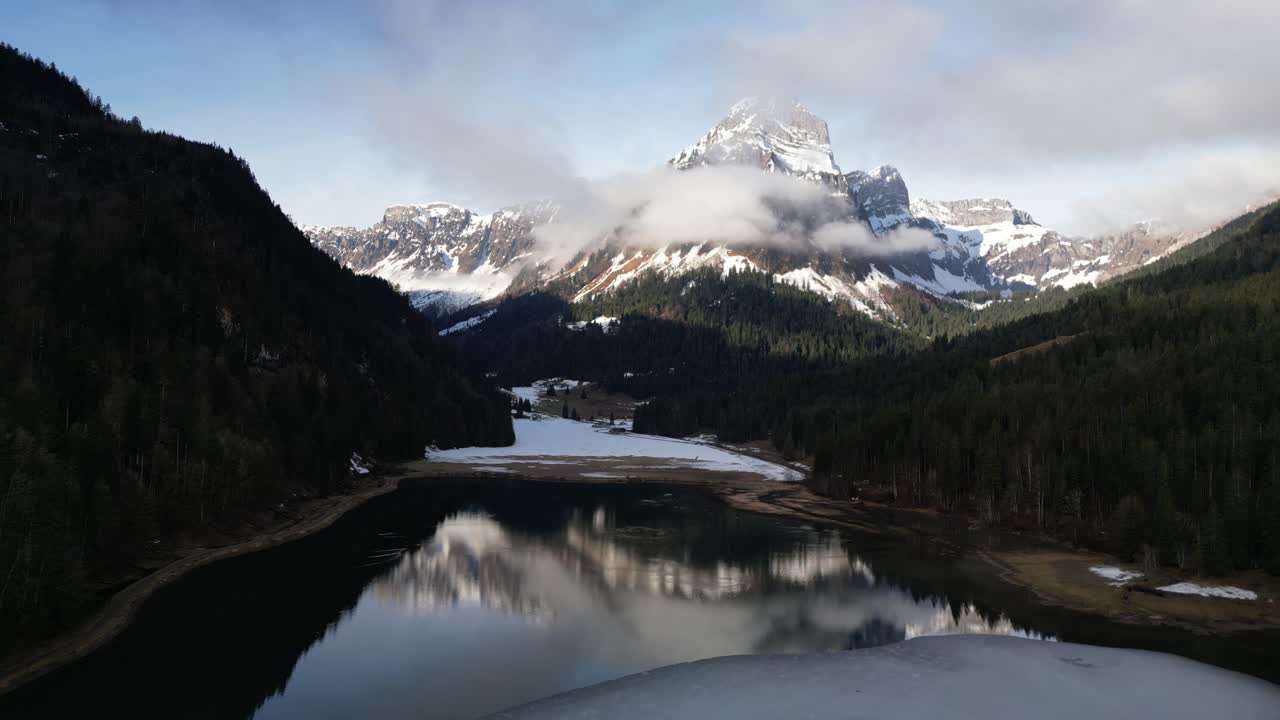 pintorescos picos cubiertos de nieve se reflejan en el agua tranquila abierta con bosque de pinos