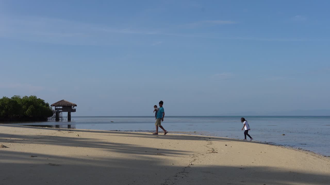 푸에르토 프린세사, 팔라완, 필리핀에 있는 도스 팔마스 섬 리조트와 스파를 배경으로 파란 하늘을 배경으로 해변에서 노는 현지 아이들