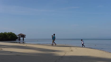 Local-Kids-Playing-On-The-Beach-Shore-With-Blue-Sky-On-The-Background-In-Dos-Palmas-Island-Resort-And-Spa-In-Puerto-Princesa,-Palawan,-Philippines