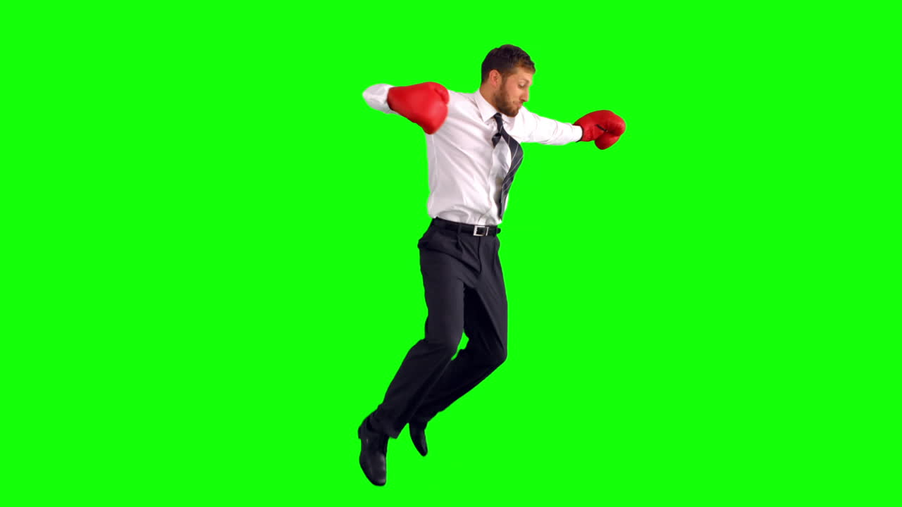 Uomo d'affari che salta con guantoni da boxe e sferra pugni