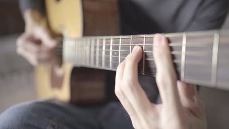 a man playing chords on acoustic guitar