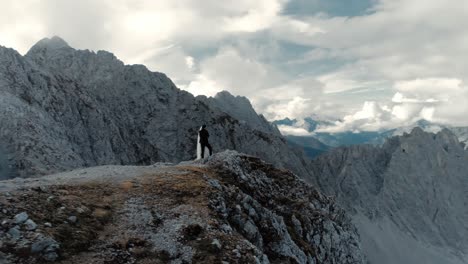 órbita aérea de una pareja en la cima de la montaña de los alpes panorámicos con un cielo lleno de nubes - paisaje cinematográfico con drones