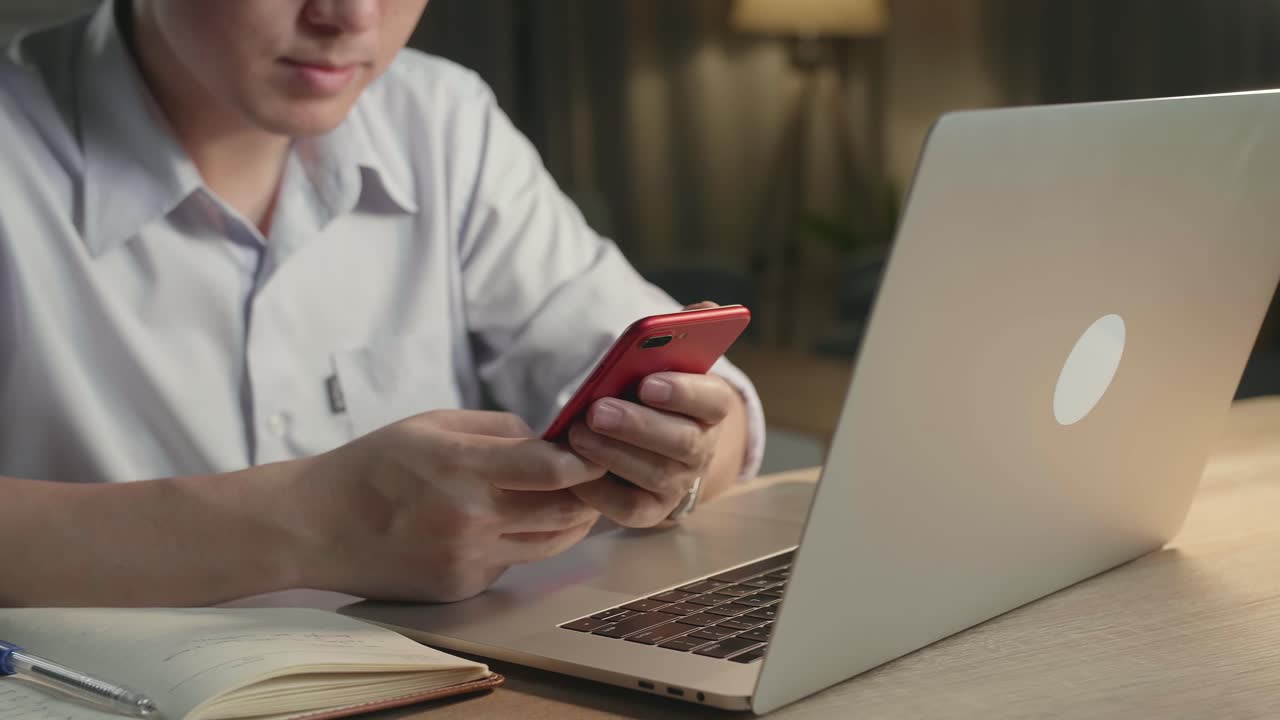 Person using smartphone and laptop at night