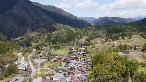 aerial view over rooftops of tsumago-juku town in nagano prefecture. dolly forward with valley view in the background