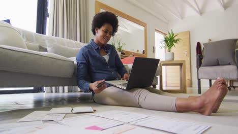 happy african american woman sitting on floor, using laptop and working