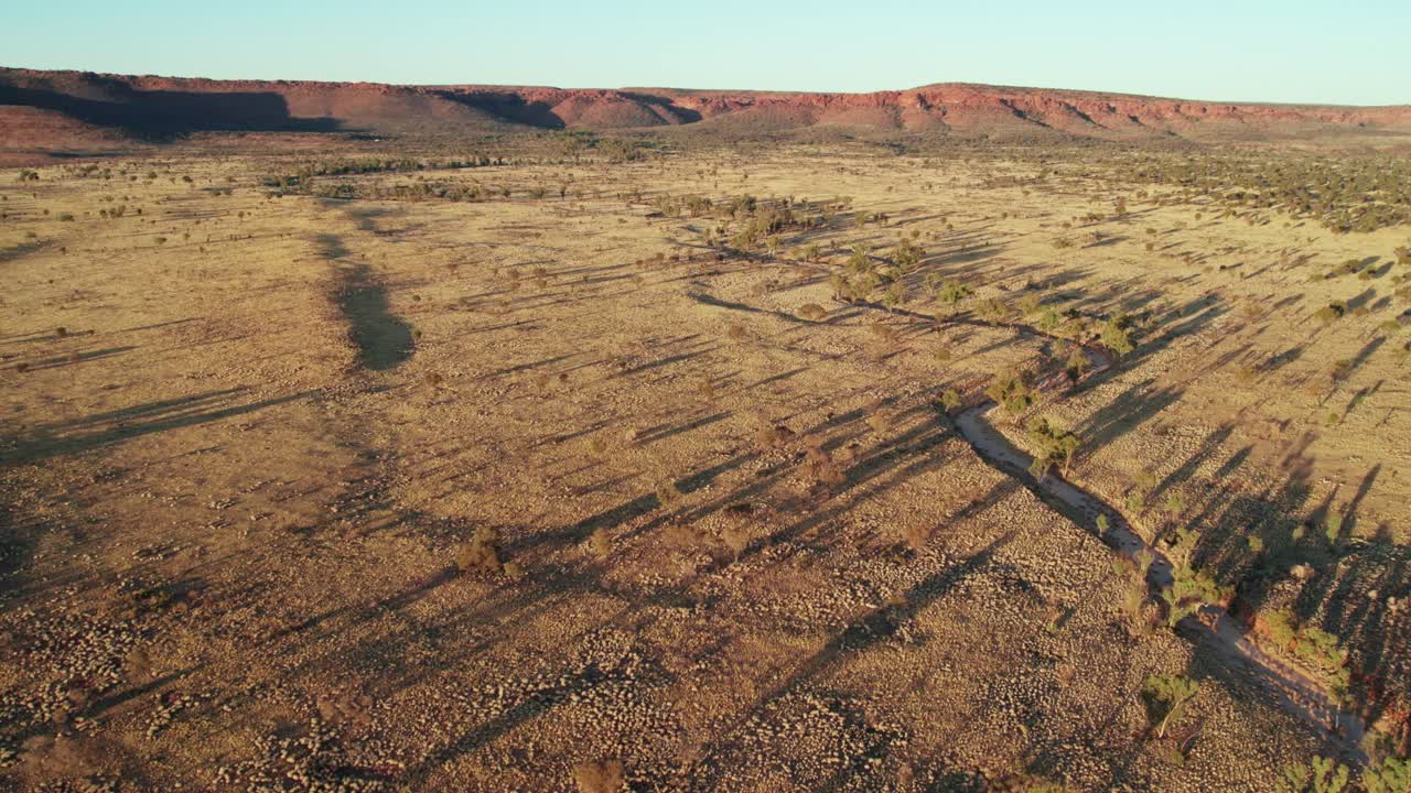 Aerial footage of a small creek and Kings Canyon, Watarrka in the background. Northern Territory, Australia. August 2022