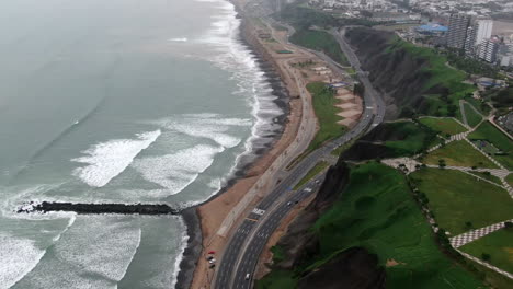 Enthüllen-Schuss-Von-Miraflores-Stadt-In-Der-Nähe-Des-Strandes-Mit-Einer-Küstenstraße-In-Peru-Aus-Der-Luft