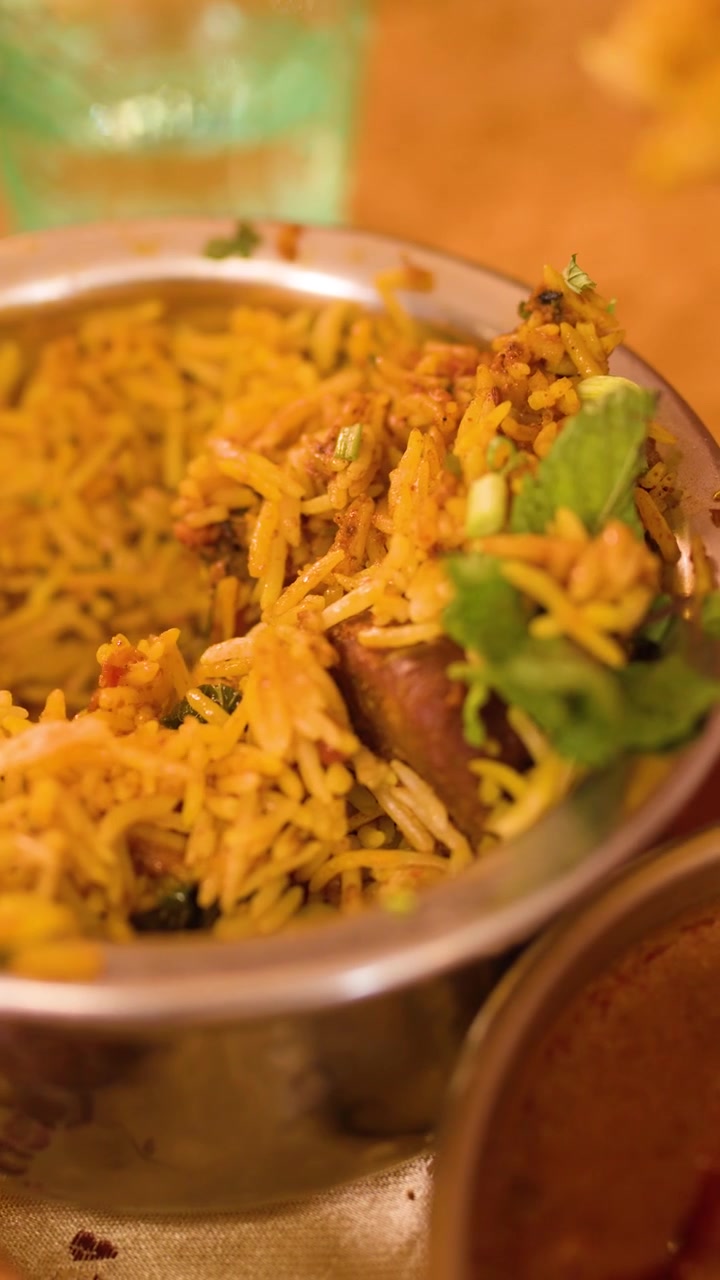 Persona sirviendo arroz Biryani indio tradicional de un cuenco de metal