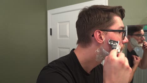 hombre con bigote afeitándose con afeitadora y crema de afeitar