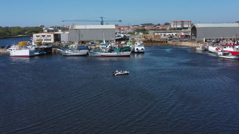 Aerial-rotation-shot-of-small-motor-boat-moving-through-quay-near-a-shipyard