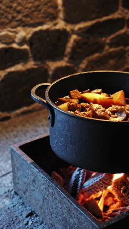 cooking stew over an open fire in a cast iron pot