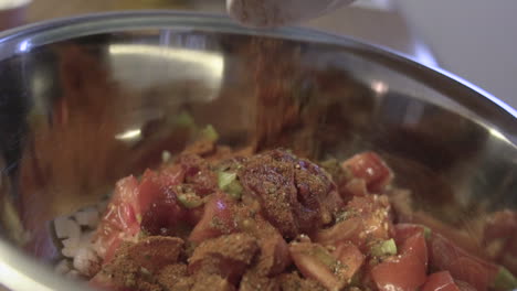 close shot as pouring smashed condiments, pepper and paprika over a bowl of vegetables as preparing a healthy vegan gluten free food