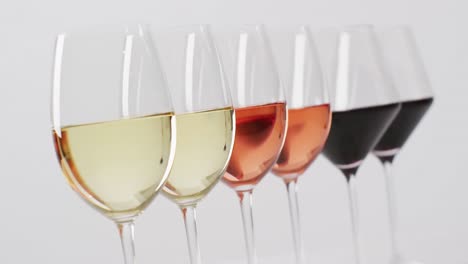 row of diverse types of wines in glasses on white surface