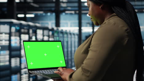 developer in data center using green screen laptop to upgrade systems