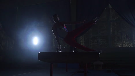 Male-gymnast-performs-Pommel-horse-exercise-in-a-dark-room-in-smoke-in-slow-motion.-Sports-for-health-and-achievement