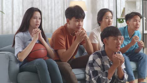 아시아 십대들이 tv에서 농구 경기를 응원하고 지켜보고 집에서 실망합니다.