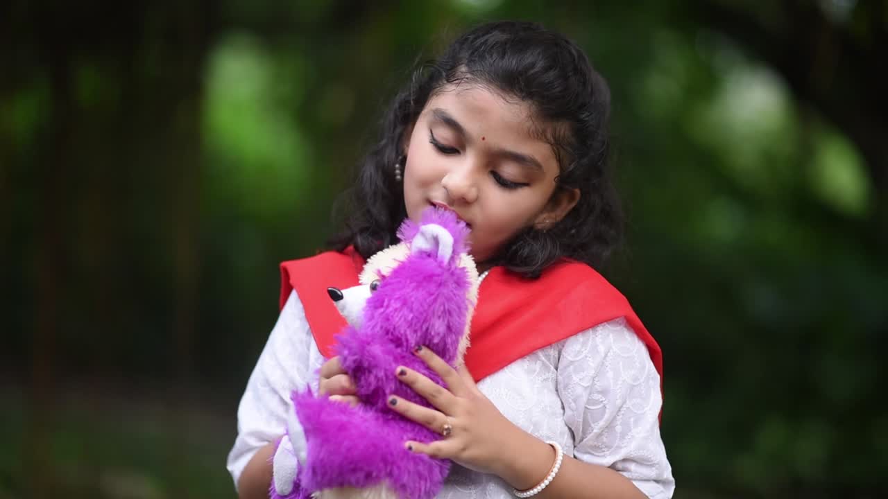 una linda niña asiática está jugando con su osito de peluche en un bosque sola el día de halloween