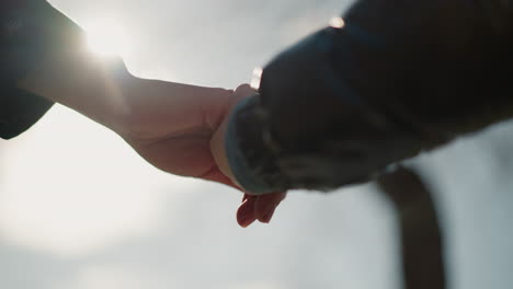 a close-up of two people holding hands stretched out, illuminated by the soft glow of sunlight