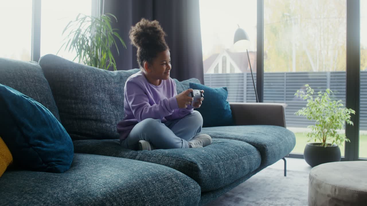 A young girl is playing video games in the living room