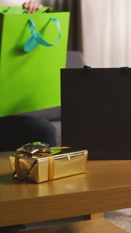 vertical video of person taking presents out of gift bags on table in lounge 1