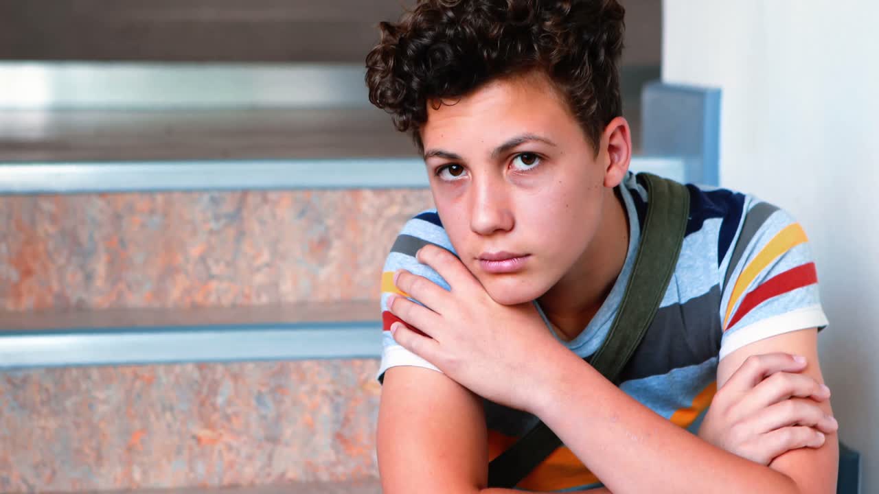 triste escolar sentado solo en la escalera