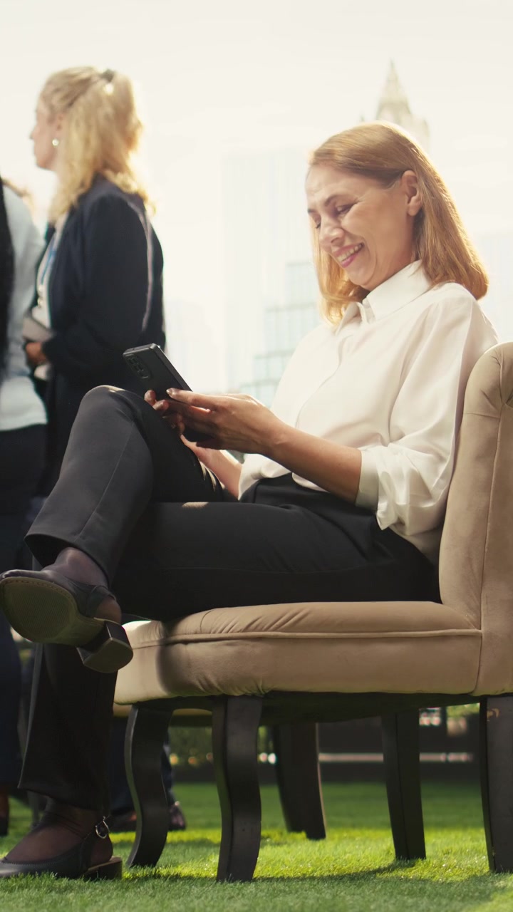 Video verticale: Donna d'affari che controlla i messaggi sullo smartphone durante la pausa lavoro sulla terrazza dell'ufficio