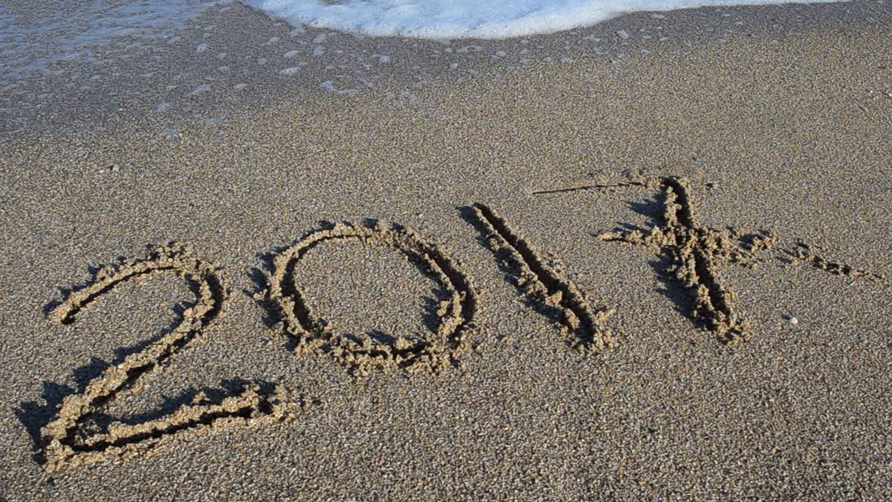 Inschrift 2017 im Sand. Die Inschrift wird von einer Meereswelle weggespült. Aufnahme am Strand