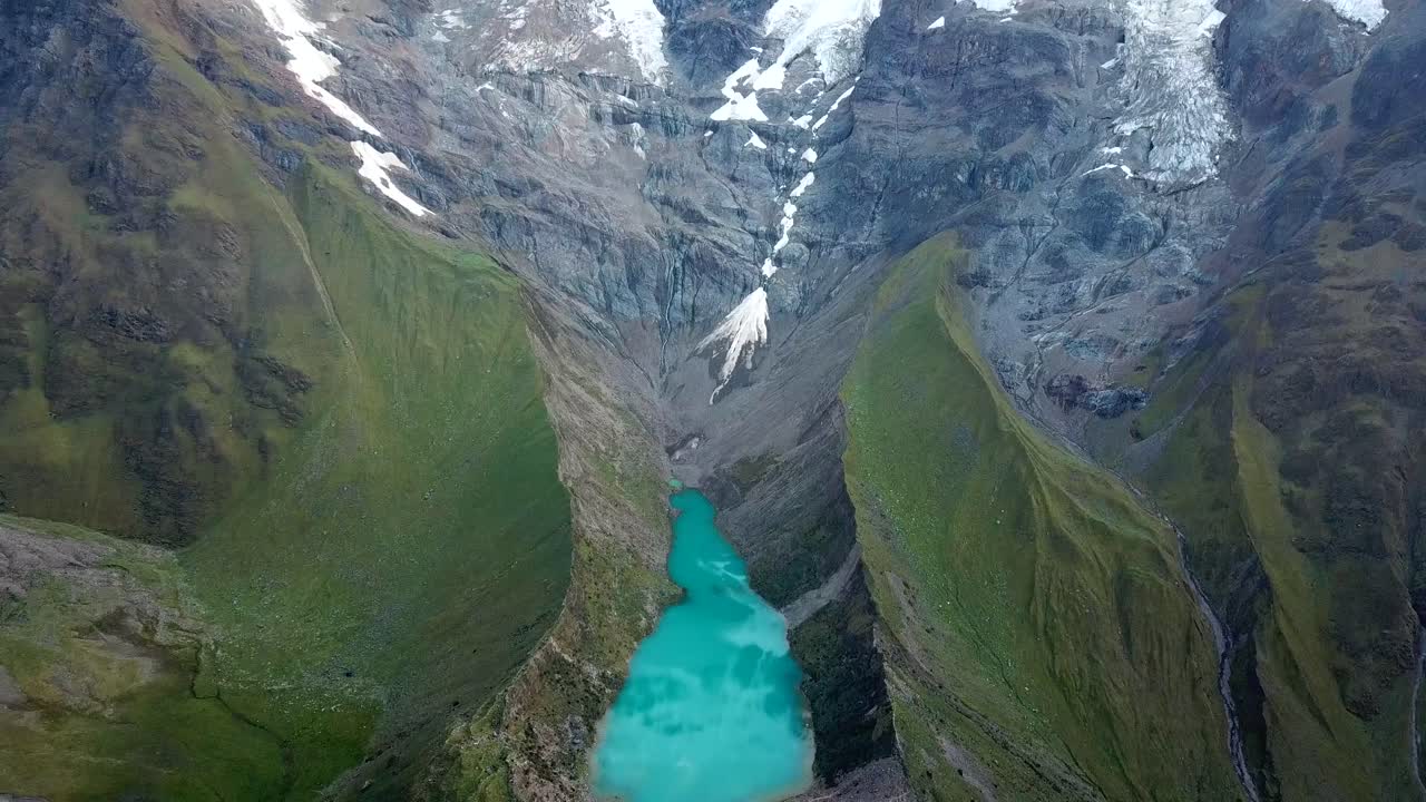 Aerial, tilt up, drone shot overlooking the Laguna Humantay lake, in Andes mountains, overcast day, in Cusco region, Peru