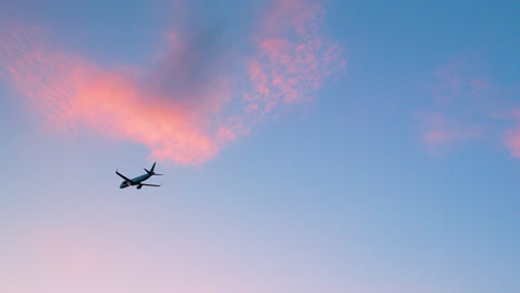 Silhouette-Eines-Flugzeugs-Am-Blauen-Himmel-Bei-Sonnenuntergang-Mit-Rosafarbenen-Wolken,-Die-Zum-Ziel-Aufbrechen