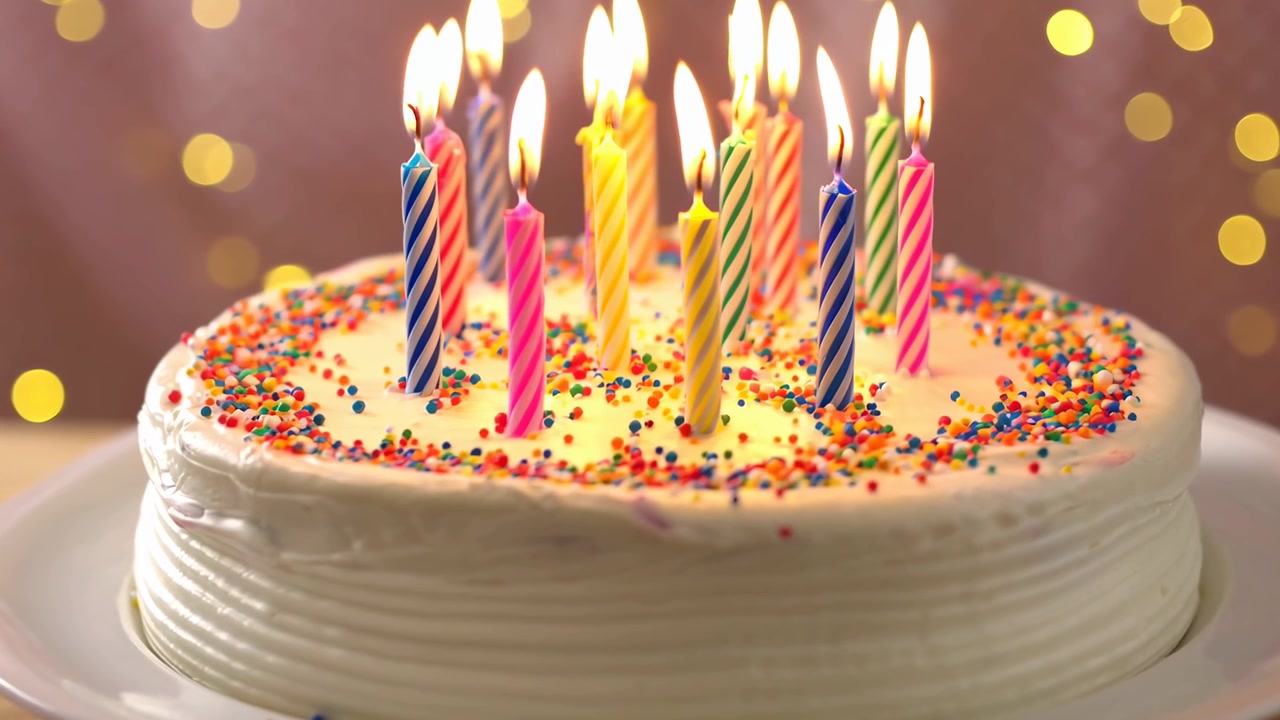 Torta di compleanno con candele accese e spruzzate colorate