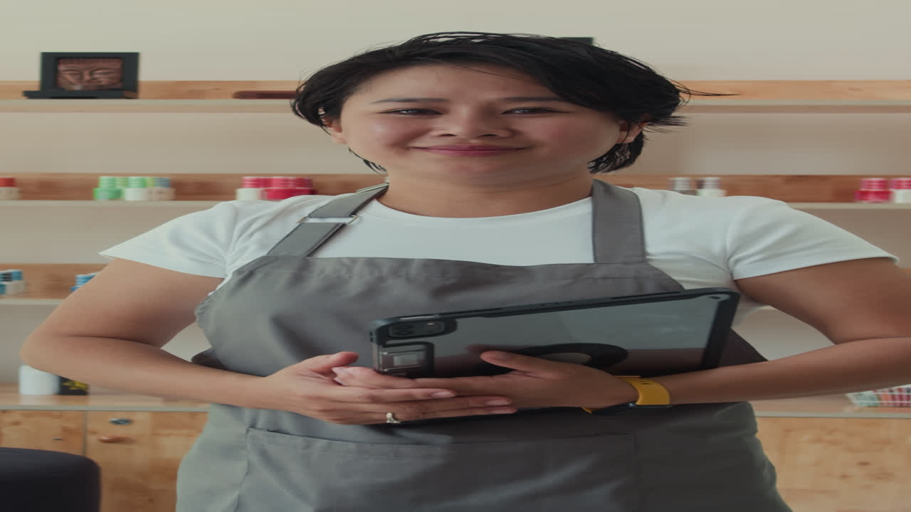 Manicurist donna che tiene in mano un tablet digitale in un salone di bellezza