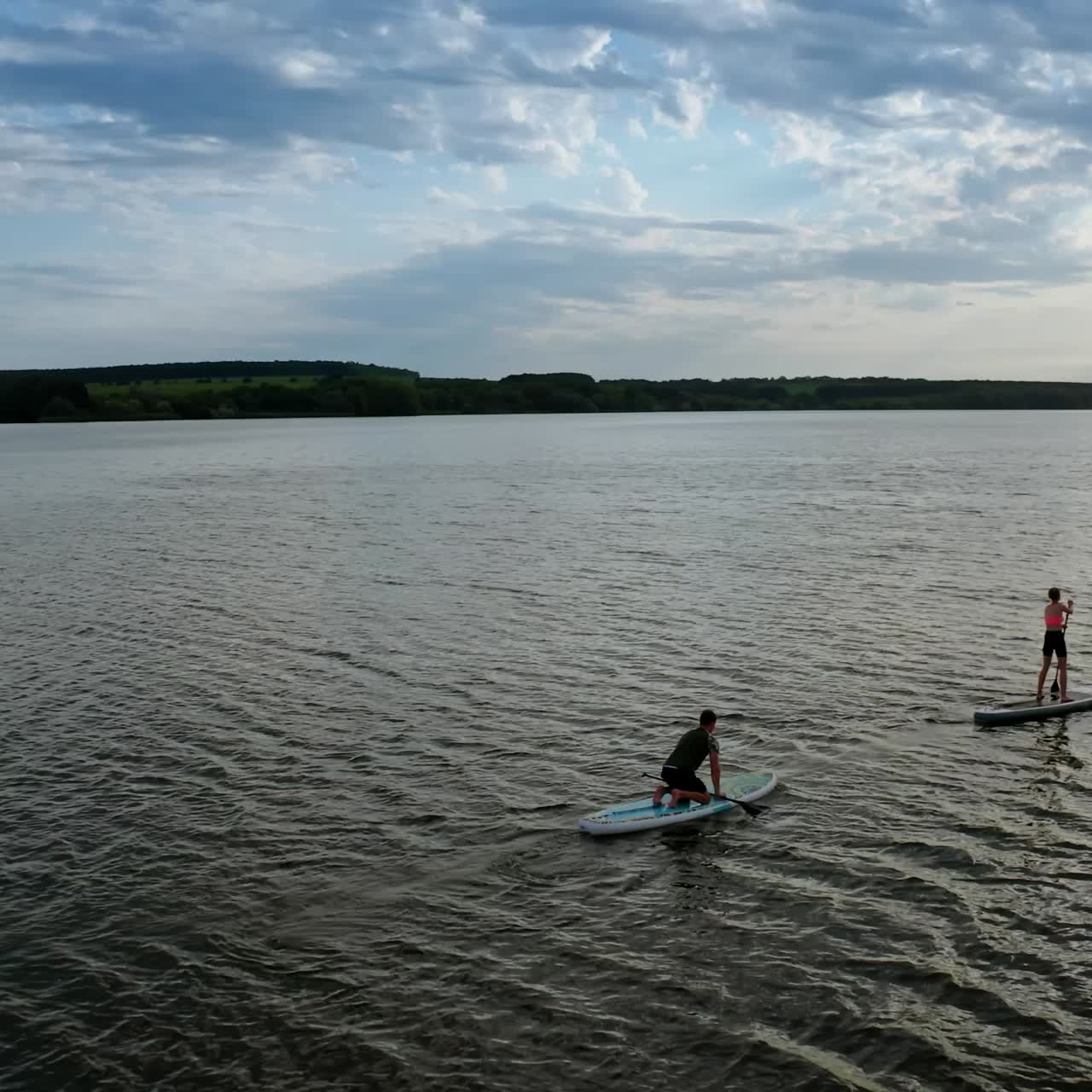 Two stand up paddlers enjoying vacation. Aerial view of active couple stand up paddling together