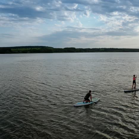 two stand up paddlers enjoying vacation. aerial view of active couple stand up paddling together