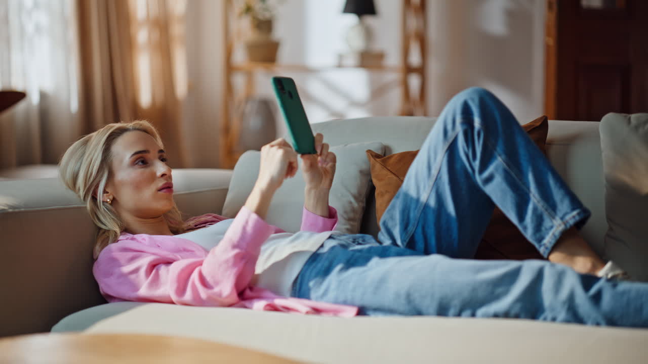 Lying woman swiping cellphone resting cozy home couch. Lady relaxing on sofa