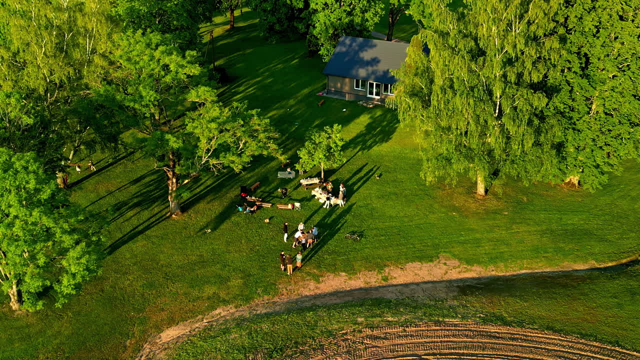⁇ 은 날 에 정원 테이블 에서 점심 을 즐기는 확장 된 가족 의 공중 드론 회전  ⁇