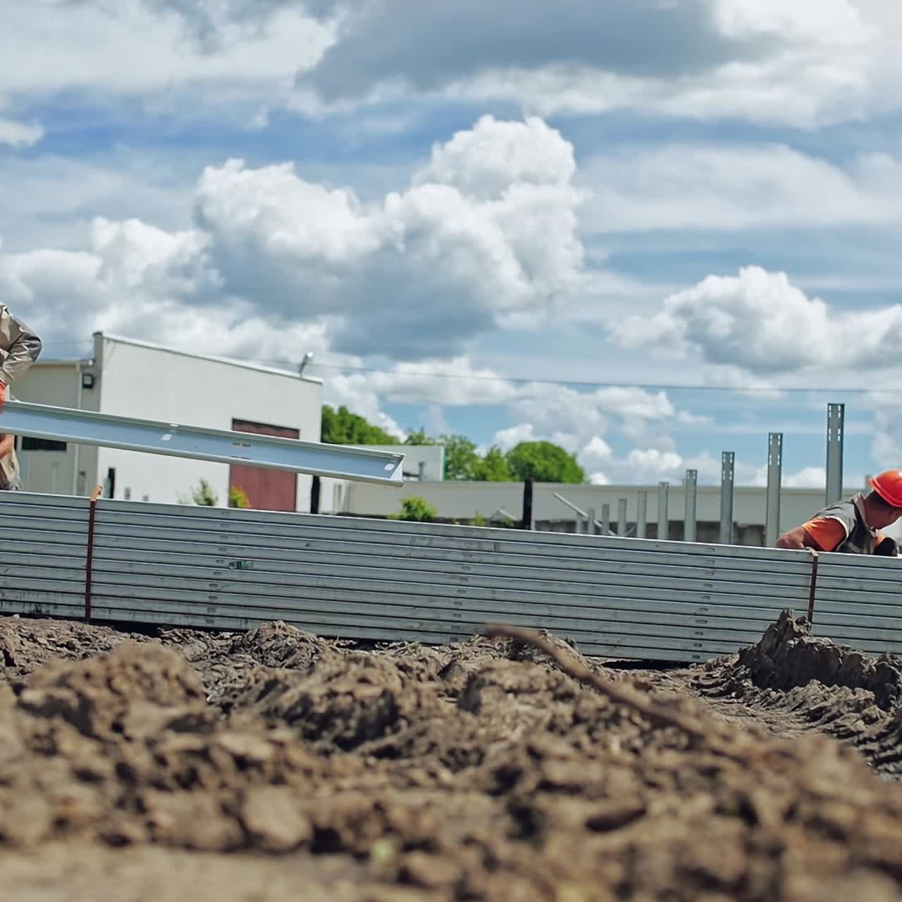 Construction solar farm. Workers in protective uniform build metal basis on the ground in summer day. Slow motion.