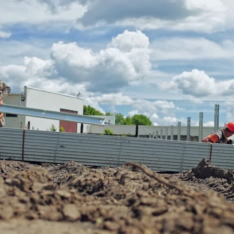 construction solar farm. workers in protective uniform build metal basis on the ground in summer day. slow motion.