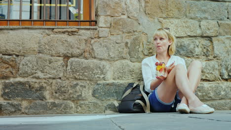un turista cansado come fruta sentado en la acera de la parte antigua de la ciudad de barcelona