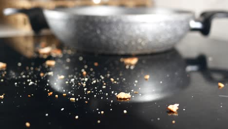 a messy stovetop with crumbs and a pan