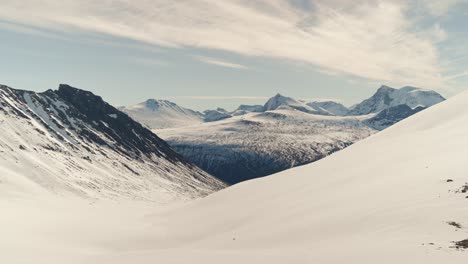 Snowy-valley-and-mountain-peaks-in-Norway,-aerial-view