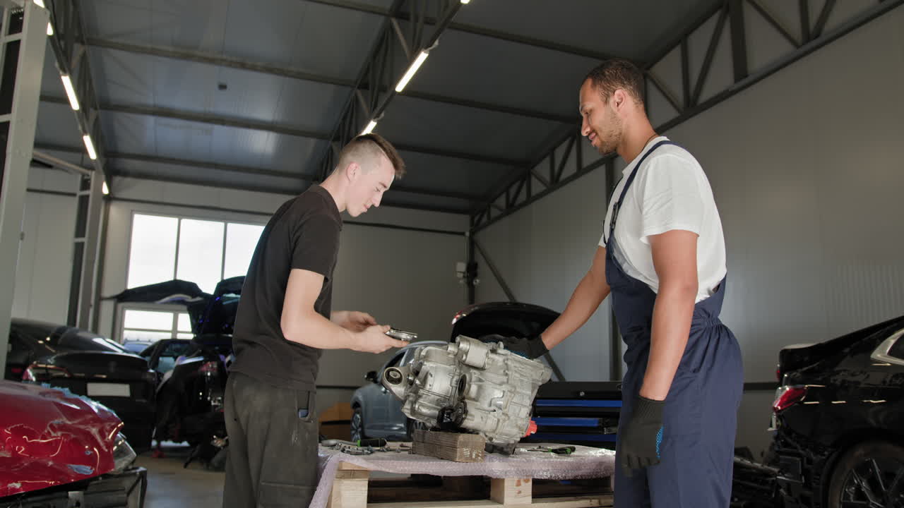 dos mecánicos trabajando en una transmisión de coche en un taller de reparación.