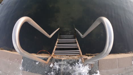 primer plano de 4k de una pequeña escalera de metal junto al agua fría del mar en un día de invierno en suecia